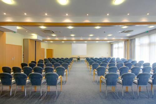 an empty room with chairs and a screen at Hotel Oberhausen Neue Mitte affiliated by Meliá in Oberhausen