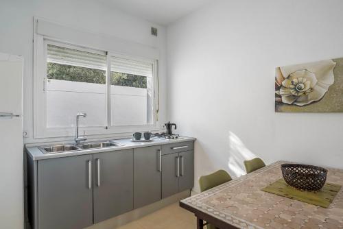eine Küche mit einem Waschbecken, einem Fenster und einem Tisch in der Unterkunft Casa Victoria in Vejer de la Frontera