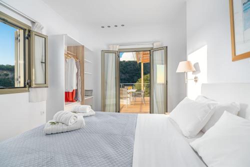 Un dormitorio blanco con una cama con toallas. en Kosyforema Villas en Gialova