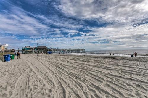a sandy beach with a pier in the background at Steps to Boardwalk Condo with Pool in Myrtle Beach in Myrtle Beach