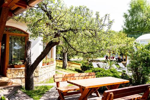 a wooden picnic table and benches in a garden at Aranybánya Panzió és Apartmanház in Telkibánya