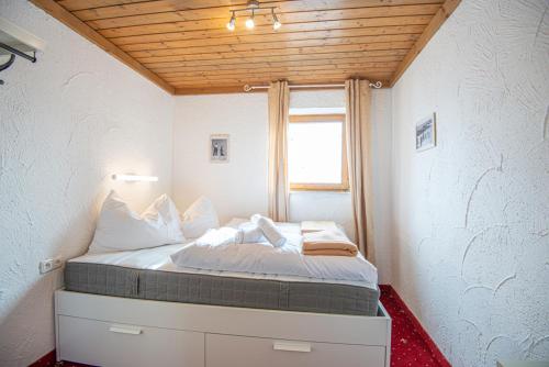 uma cama num pequeno quarto com uma janela em Schanzerhütte em Saalbach-Hinterglemm