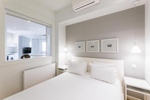 a white bedroom with a bed and a window at Lori Margariti Sea View Flat in Thessaloniki
