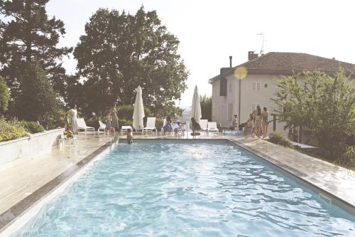 uma grande piscina com cadeiras e um edifício em Villa Trisano em Bra