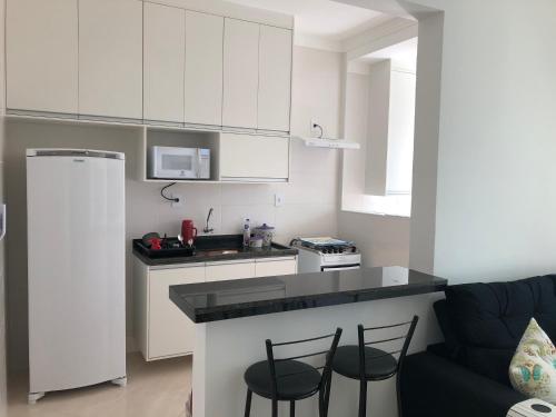 a kitchen with white cabinets and black counter tops at AP 71 COSTA VERDE PRAIA GRANDE in Praia Grande