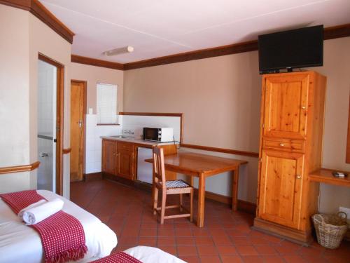 a room with a desk and a kitchen in a room at Oakwood Lodge in Bloemfontein