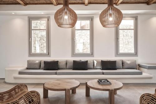 a living room with a couch and two tables and two windows at Radisson Blu Euphoria Resort, Mykonos in Kalo Livadi