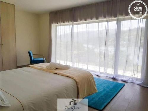 ein Schlafzimmer mit einem Bett und einem großen Fenster in der Unterkunft ERMAL HOUSE in Braga