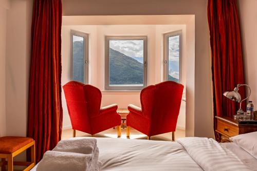 a bedroom with two red chairs and a window at The Lodge On The Loch Onich in Onich
