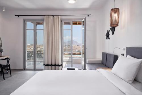 a white bedroom with a large bed and a balcony at Radisson Blu Euphoria Resort, Mykonos in Kalo Livadi