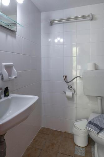 a white bathroom with a sink and a toilet at Faro Del Porto in Póros Kefalonias