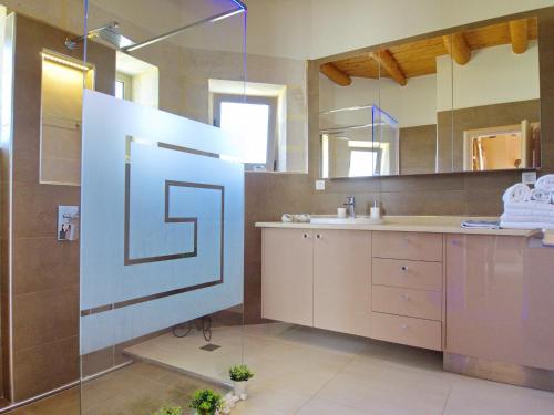 Un baño con lavabo y ducha con espejo. en Villa Olivia with Pool Vrises Crete, en Alikampos