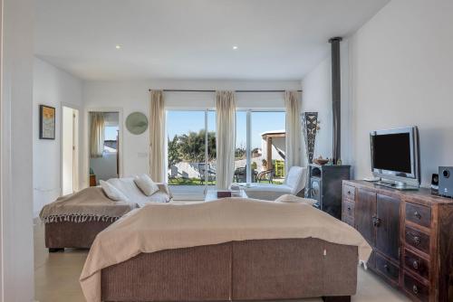 ein Schlafzimmer mit einem Bett, einem Fernseher und einer Couch in der Unterkunft Casa Victoria in Vejer de la Frontera