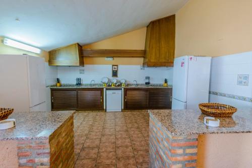 uma cozinha com armários de madeira e um frigorífico branco em La Posada de Rivero em Rivero de Posadas
