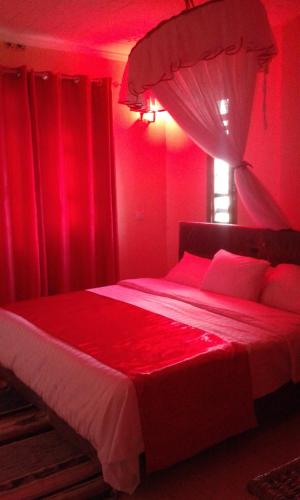 a red bedroom with a bed with red curtains at Hilda Blooms in Kisumu