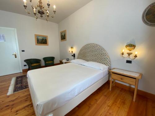 a bedroom with a large white bed and a chandelier at Villa Ca' Damiani Rooms & Apartments in Caneva