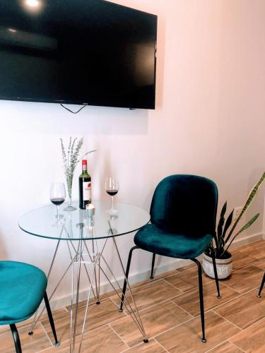 a glass table with two chairs and a bottle of wine at Urban Oasis Aparthotel in Cape Town