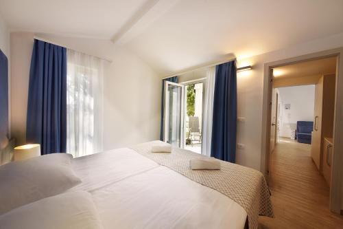 una camera da letto con un grande letto bianco con tende blu di Olive Family Suites - Hotel & Resort Adria Ankaran ad Ancarano