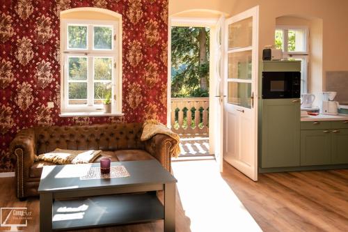 a living room with a couch and a kitchen at Kavalierhaus im Rhododendronpark Kromlau in Gablenz