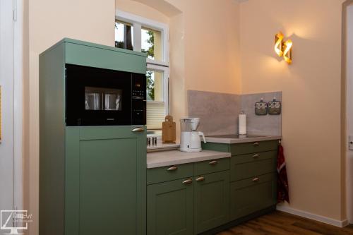 a kitchen with a green cabinet with a microwave at Kavalierhaus im Rhododendronpark Kromlau in Gablenz