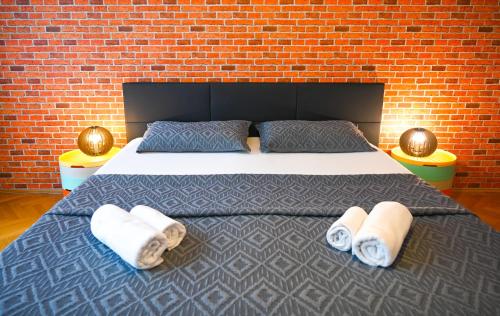 ein Schlafzimmer mit einem Bett mit Handtüchern und einer Ziegelwand in der Unterkunft Elegant Suite Augarten in Wien