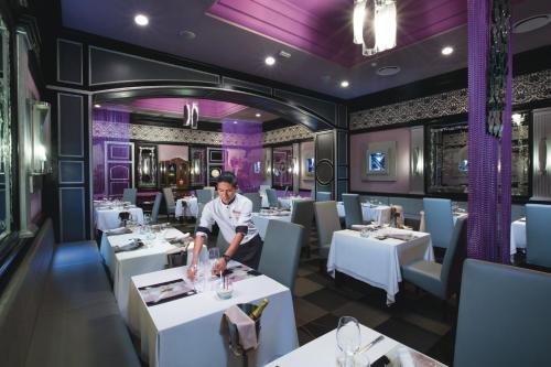a chef standing in a dining room with tables at Riu Palace Las Americas - All Inclusive - Adults Only in Cancún