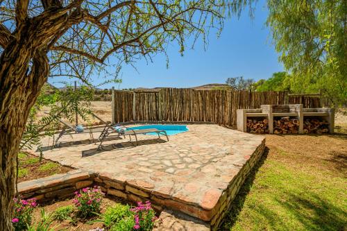 a backyard with a stone patio and a swimming pool at Glen Harry Game Reserve in Graaff-Reinet