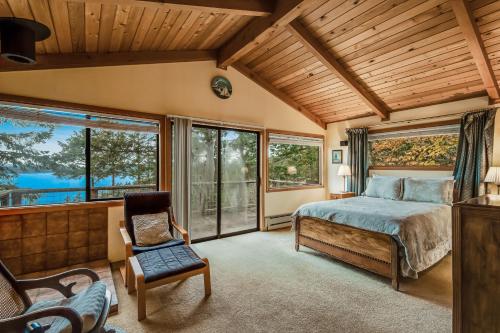 a bedroom with a bed and a chair and windows at Owl Lane Home in Orcas