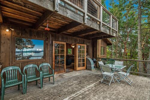 a cabin with a deck with chairs and a table at Owl Lane Home in Orcas