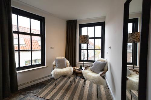 a living room with two chairs and a table and windows at Hotel-restaurant "Lely" in Oude-Tonge