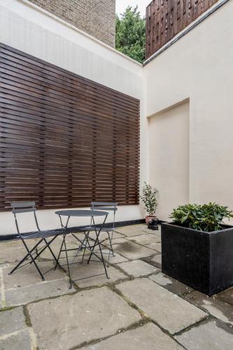 a patio with a table and chairs in front of a building at Stay Kula London - Victoria in London