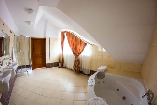 a large bathroom with a tub and a window at Hotel Stodółka in Kielce