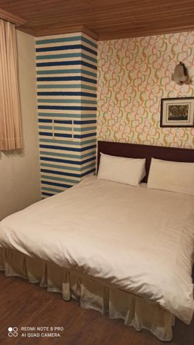 a large white bed in a room with a wall at Fengmao Hotel in Hualien City