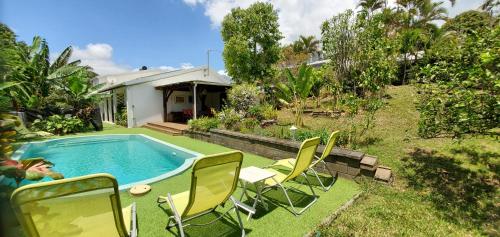a backyard with a pool and chairs and a house at La Maison Dakoté in Sainte-Clotilde