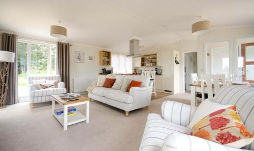 a living room with white furniture and a kitchen at Hollicarrs - Woodland Lodge in York