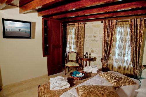 una camera con letto, sedia e tavolo di Antica Dimora Suites a Rethymno