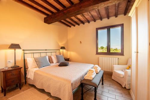 um quarto com uma cama, uma cadeira e uma janela em Le Sorelle, Minnie's Cottage em Montalcino