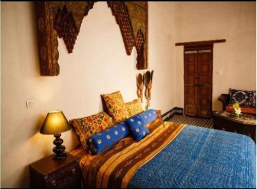 a bedroom with a bed with blue pillows and a lamp at Riad Idrissy in Fez