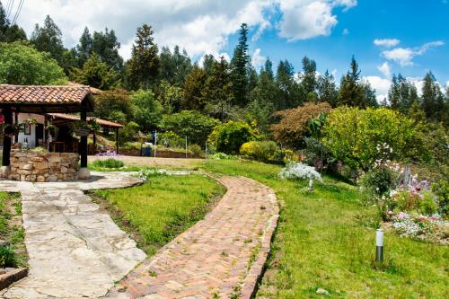 a garden with a stone path and a house at Villa Patty in Tibasosa