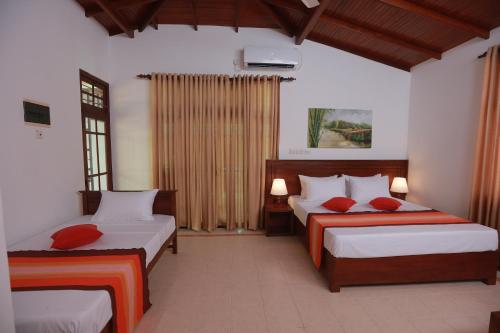 Un dormitorio con dos camas con almohadas rojas. en Villa 59, en Galle