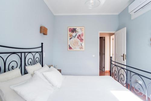 ein weißes Schlafzimmer mit einem schwarzen Bett und weißen Kissen in der Unterkunft A Casa da Joana in Costa da Caparica