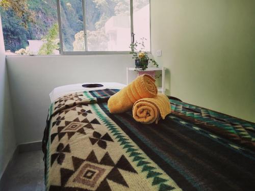 a bed with towels on it in a room with a window at Hostal & Spa Casa Real in Baños