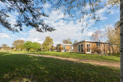 a house in a park with a tree at Welcome in - Vakantiepark Fort den Haak I Nabij strand en Veerse meer in Vrouwenpolder