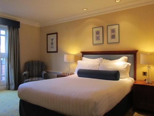 a hotel room with a large bed and a chair at Manor Hotel Solihull, BW Signature Collection in Bickenhill