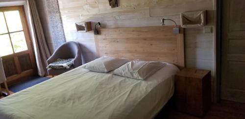 a bedroom with a white bed with a wooden headboard at Chambres d'Hôtes - Les Bujours in Saint-Georges-des-Côteaux
