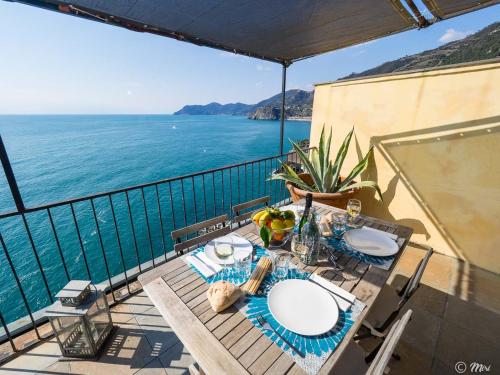 a table on a balcony with a view of the ocean at La Lampara Sea View Terrace Apartment in Manarola