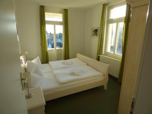 ein weißes Bett in einem Zimmer mit 2 Fenstern in der Unterkunft "Villa Loni" Ferienwohnung 7 in Ostseebad Sellin