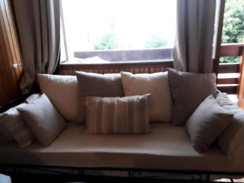 a white couch with pillows in front of a window at Residence Bellevue - maeva Home in Orcières