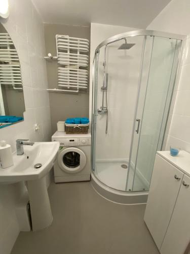 a bathroom with a shower and a washing machine at Apartament Arkońska in Szczecin