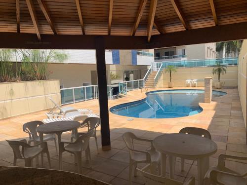 a patio with tables and chairs and a swimming pool at APTO UBATUBA-PRAIA GRANDE-CONDOMÍNIO DUBAI in Ubatuba